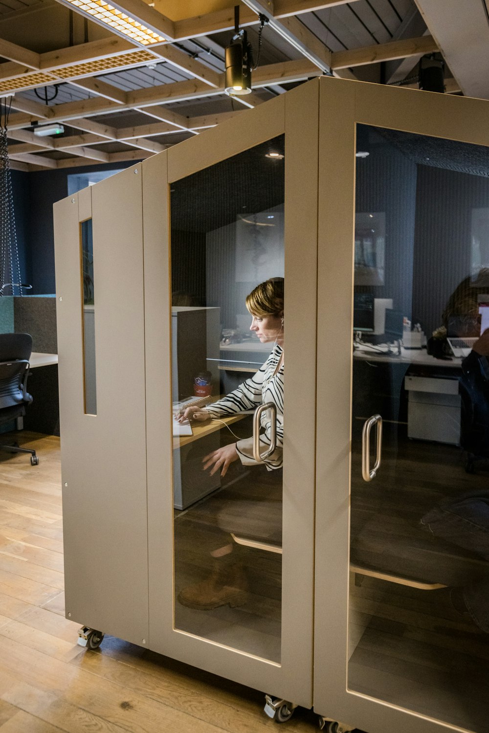 a woman sitting at a desk inside of a glass case