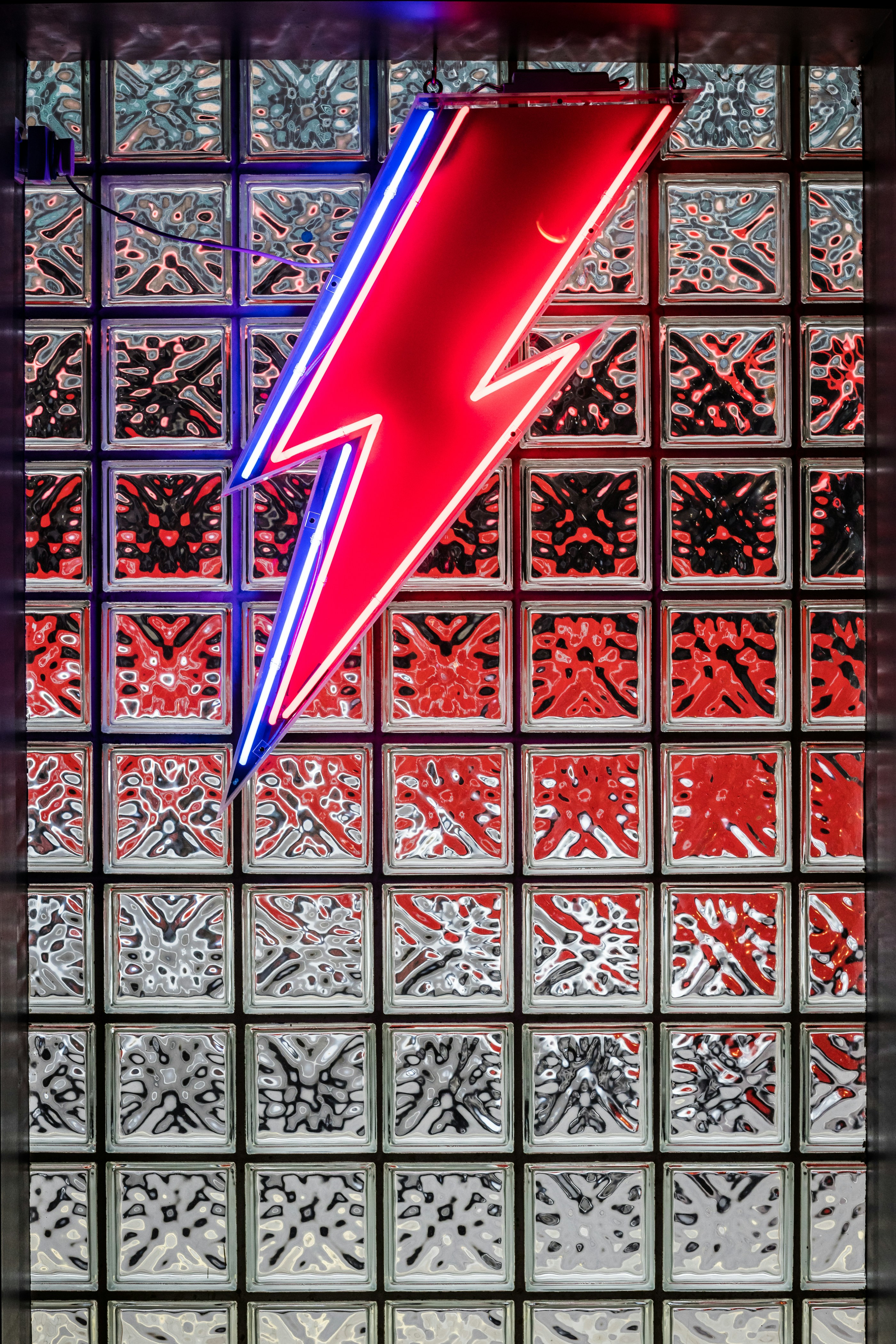 Un letrero de neón rojo y azul frente a una pared de vidrio