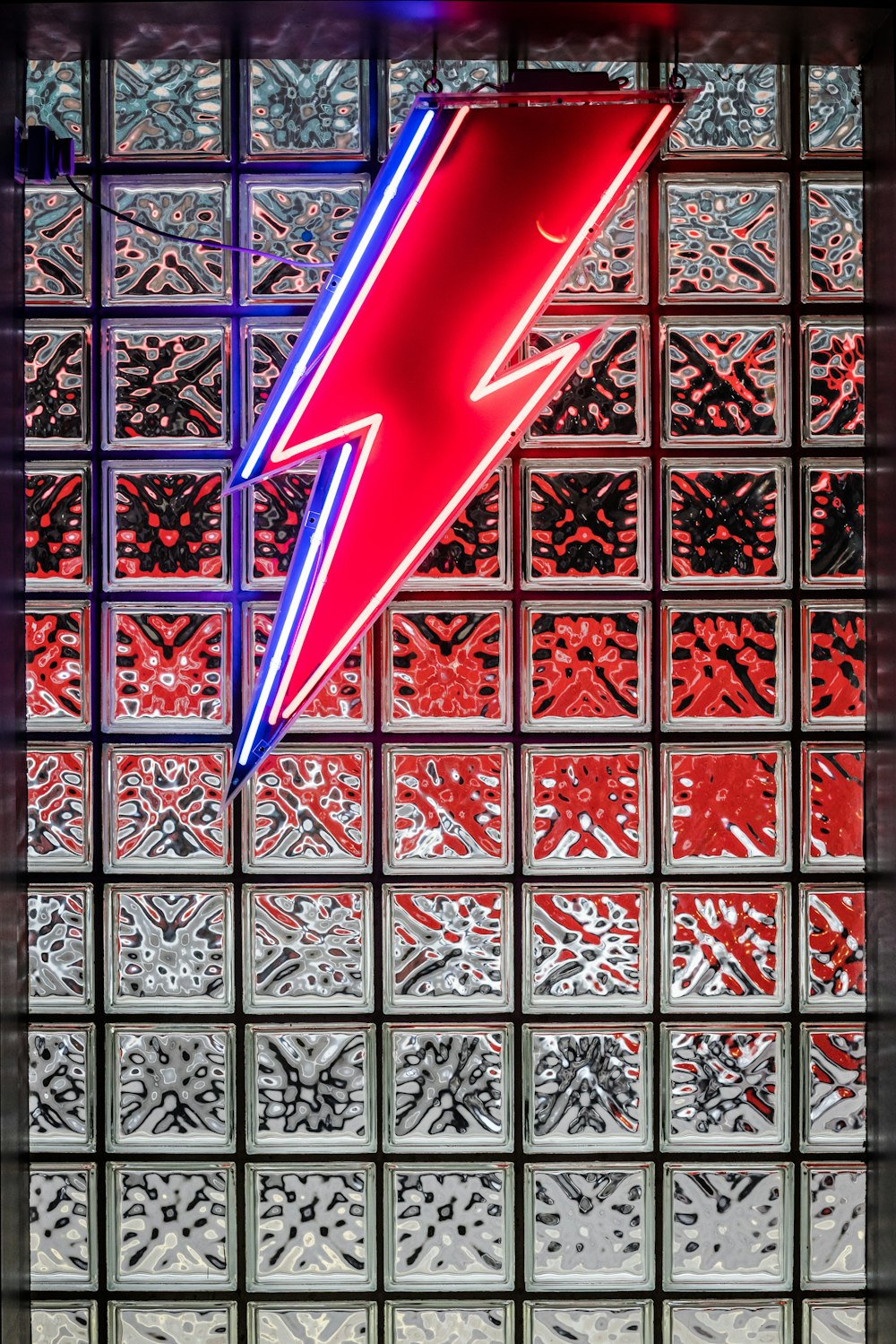 a red and blue neon sign in front of a glass wall