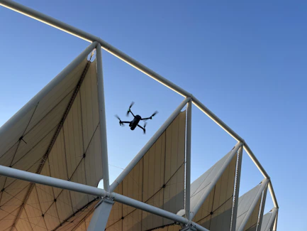a small airplane flying over a large white structure