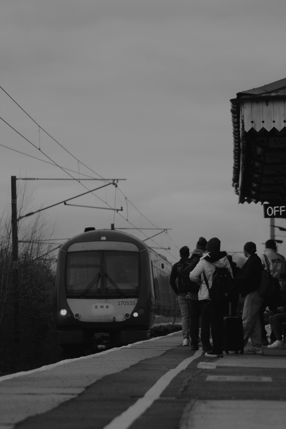 a black and white photo of people waiting at a train station