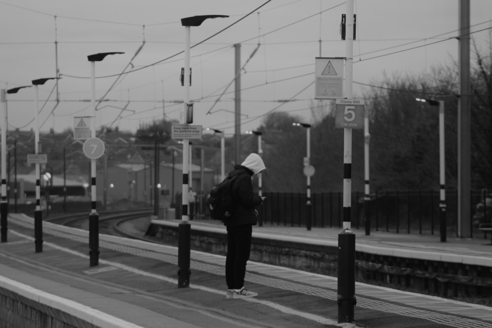 a person standing at a train station waiting for a train