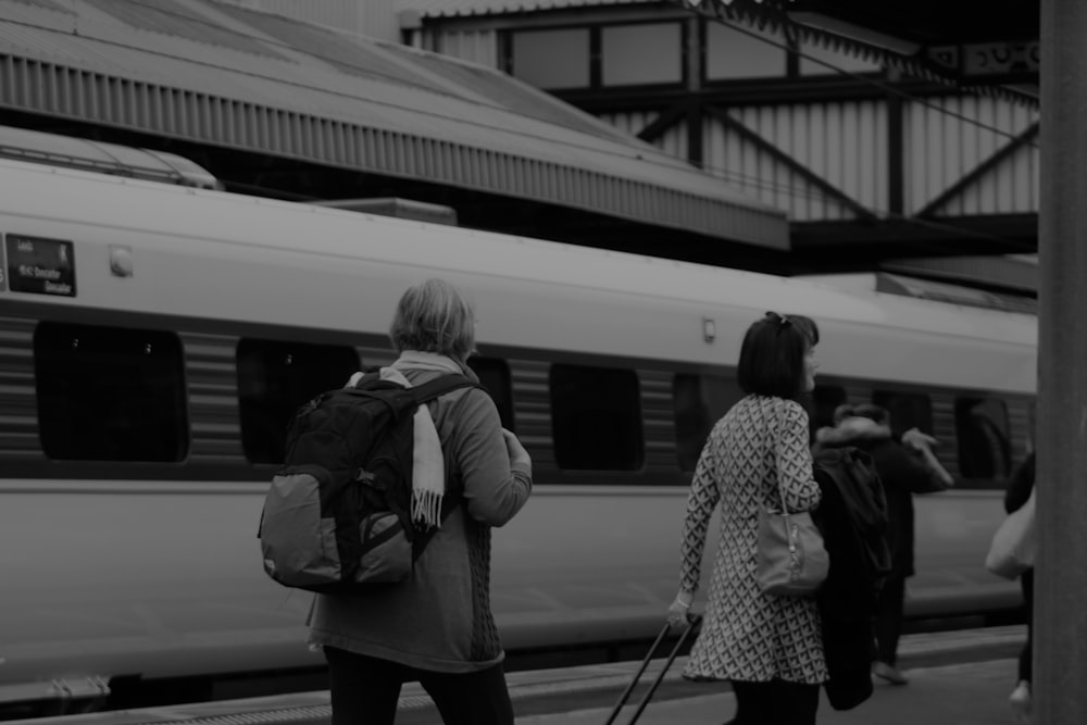 a group of people standing next to a train