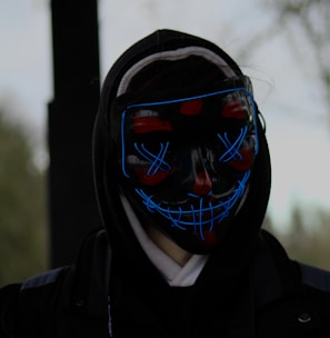 a person wearing a neon mask and a black jacket