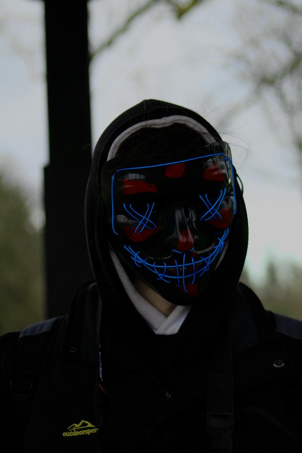 a person wearing a neon mask and a black jacket