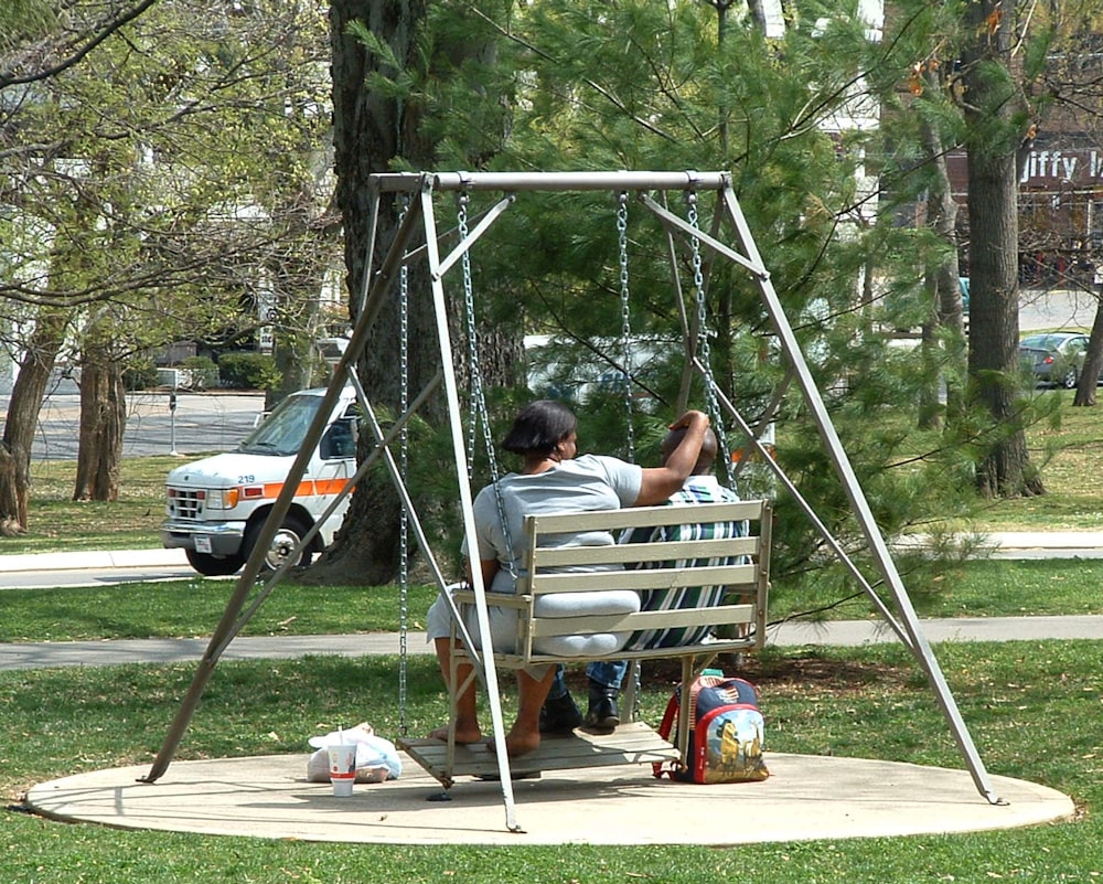 a man sitting on a swing in a park
