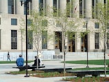two people sitting on a bench in front of a building