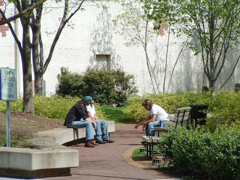 two people sitting on a bench in a park