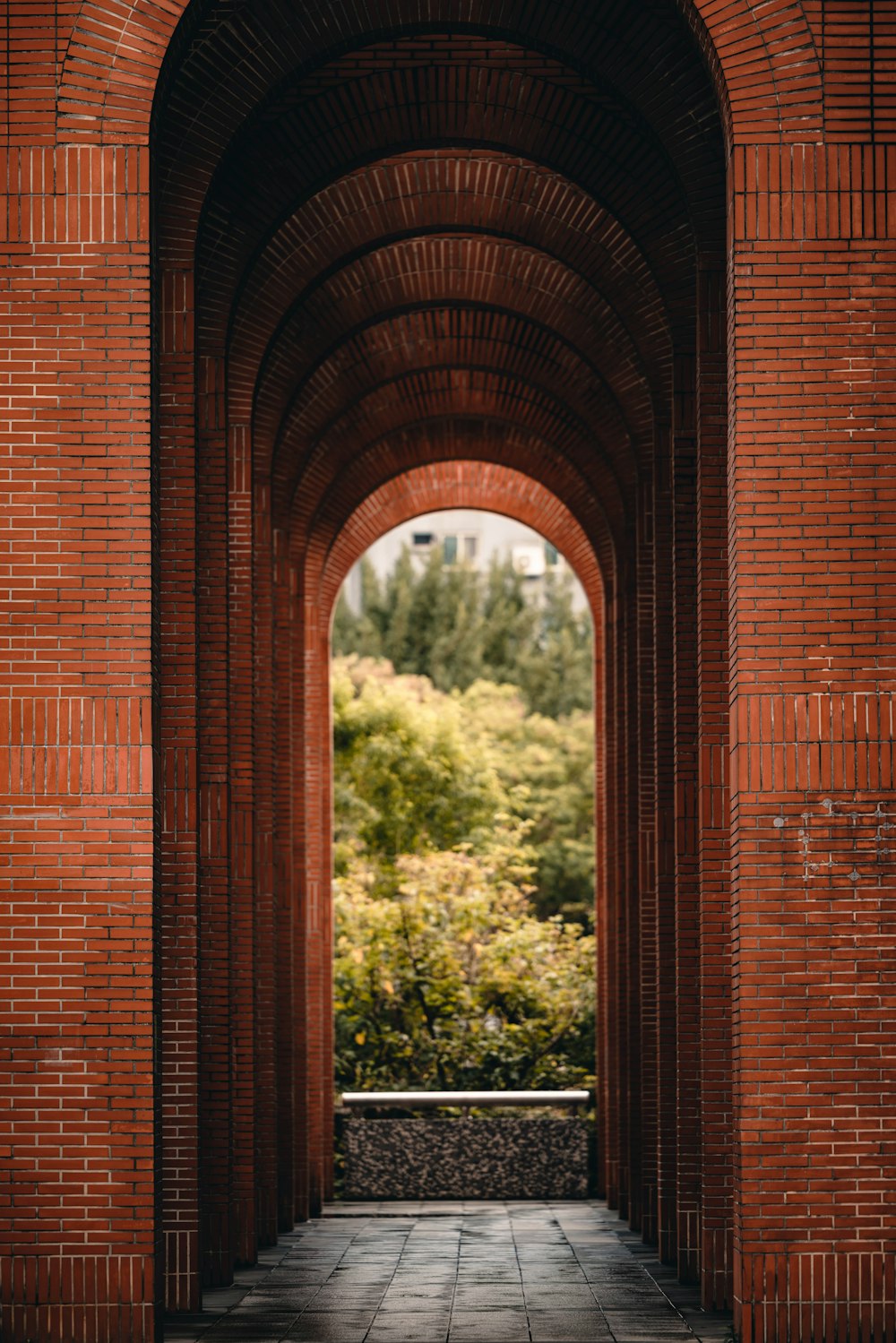 a brick archway leading into a lush green park