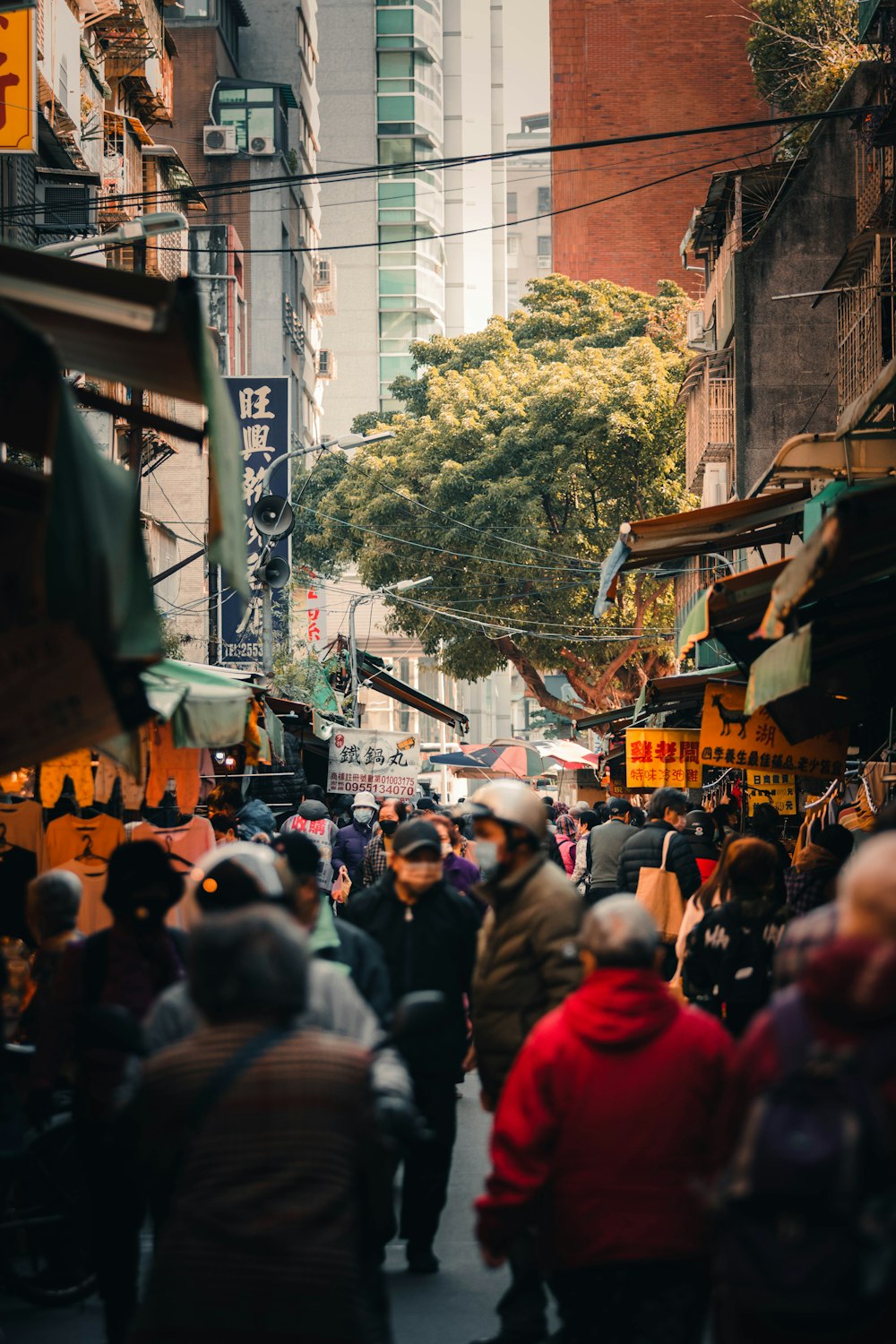 a crowd of people walking down a street next to tall buildings