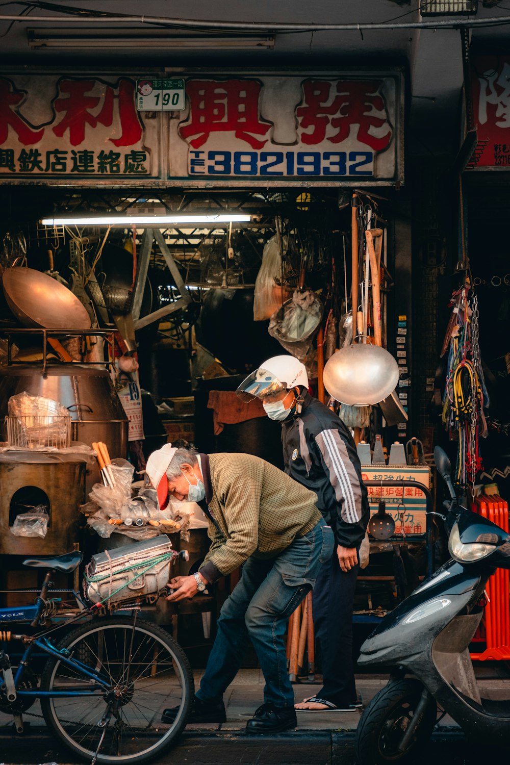 two men working on a motorcycle in front of a store