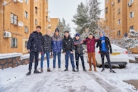 A group of volunteers handing out winter hats and gloves to homeless youth on a snowy street.