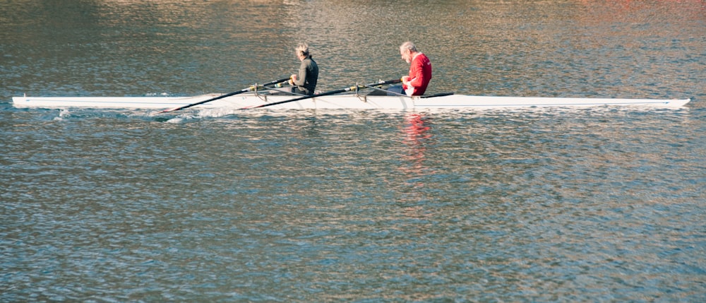 two men rowing a boat on a body of water