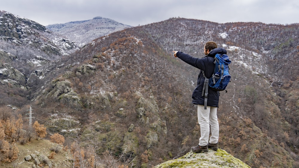 a man standing on top of a mountain with a backpack