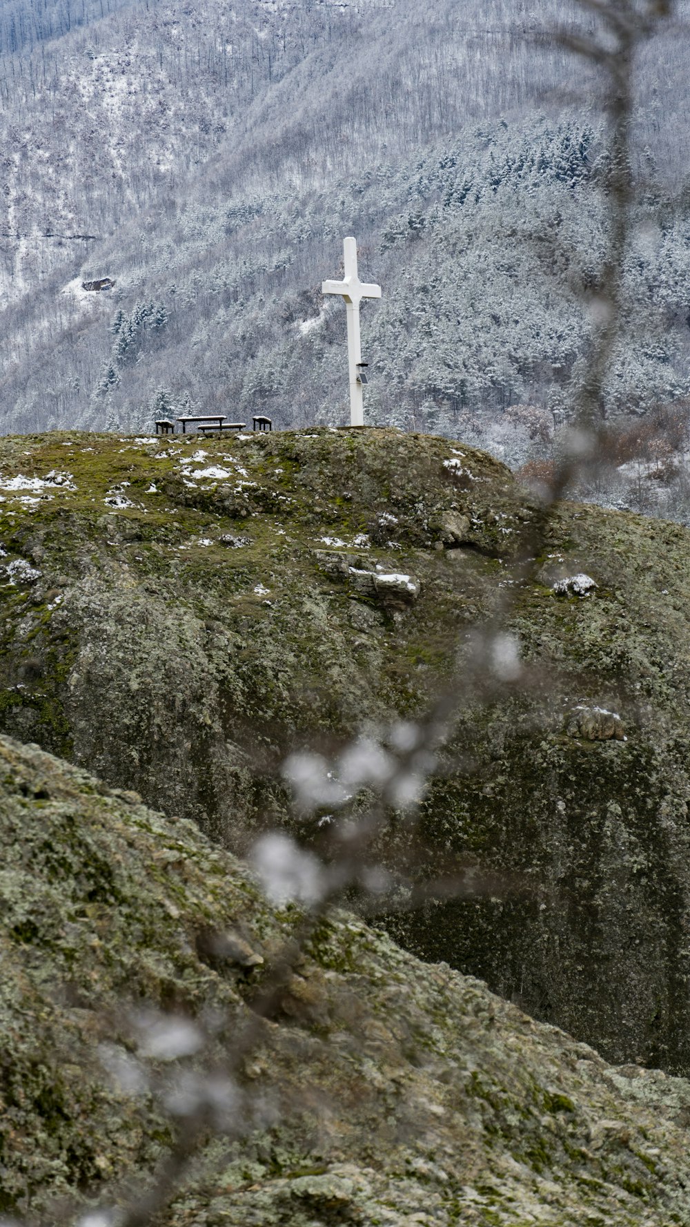 a cross on top of a hill with a mountain in the background