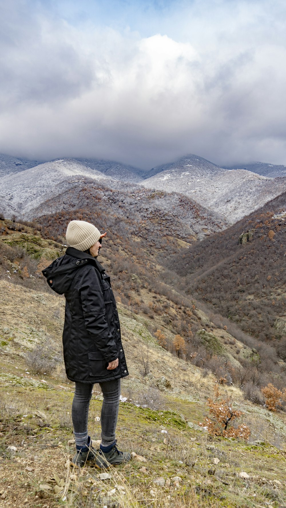 a woman standing on top of a grass covered hillside