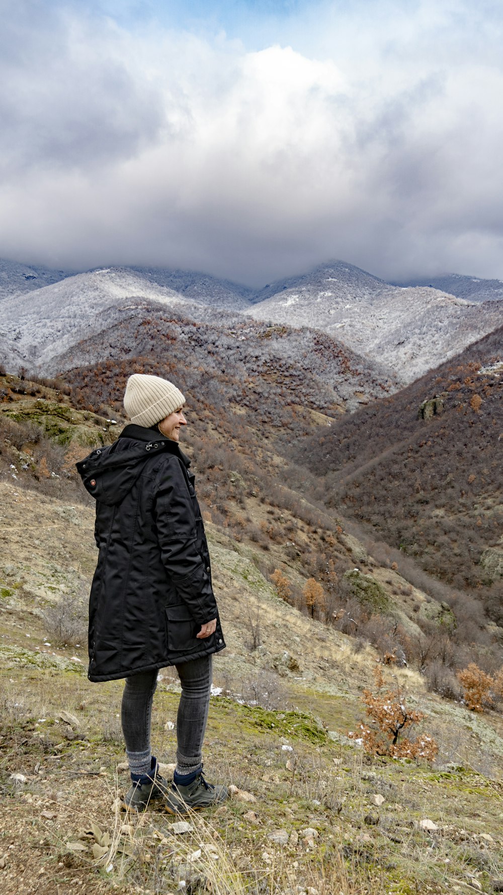 a woman standing on top of a grass covered hillside