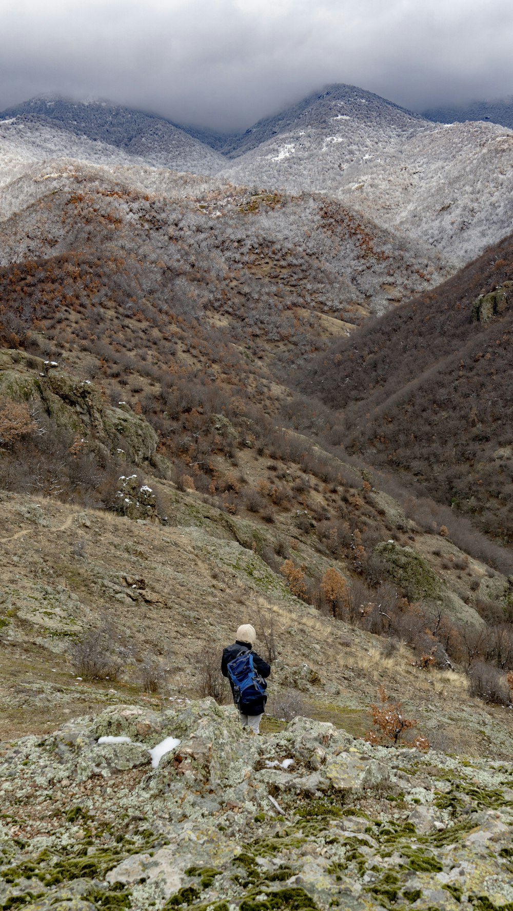 a person walking up a hill with mountains in the background