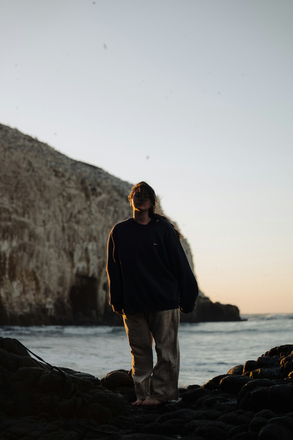 a man standing on a rocky beach next to the ocean