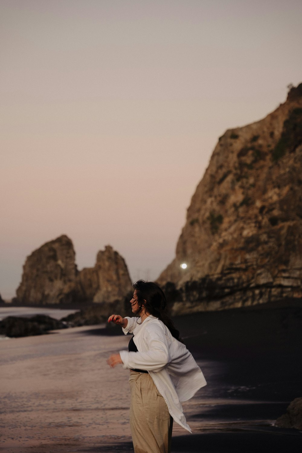 a woman standing on top of a beach next to the ocean