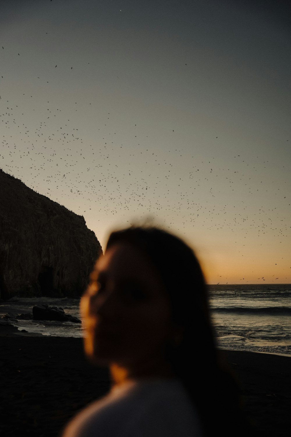 a woman standing on top of a beach next to the ocean