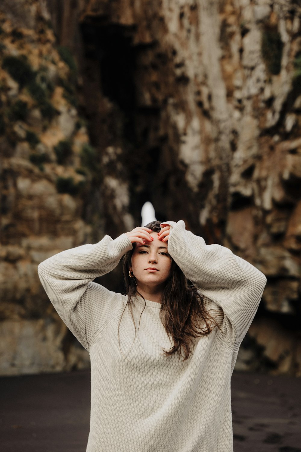 a woman standing in front of a cliff with her hands on her head