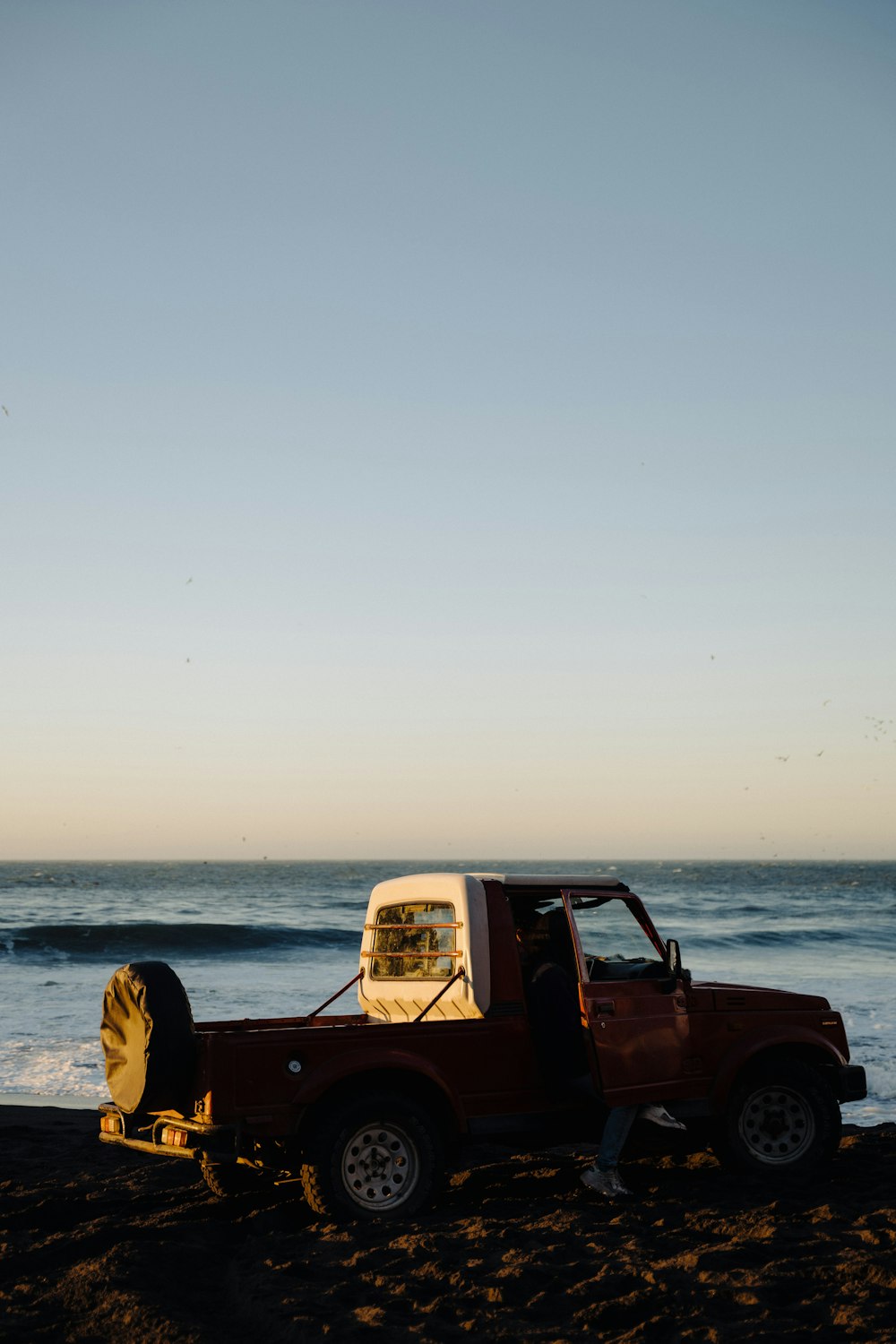 a red truck parked on top of a sandy beach
