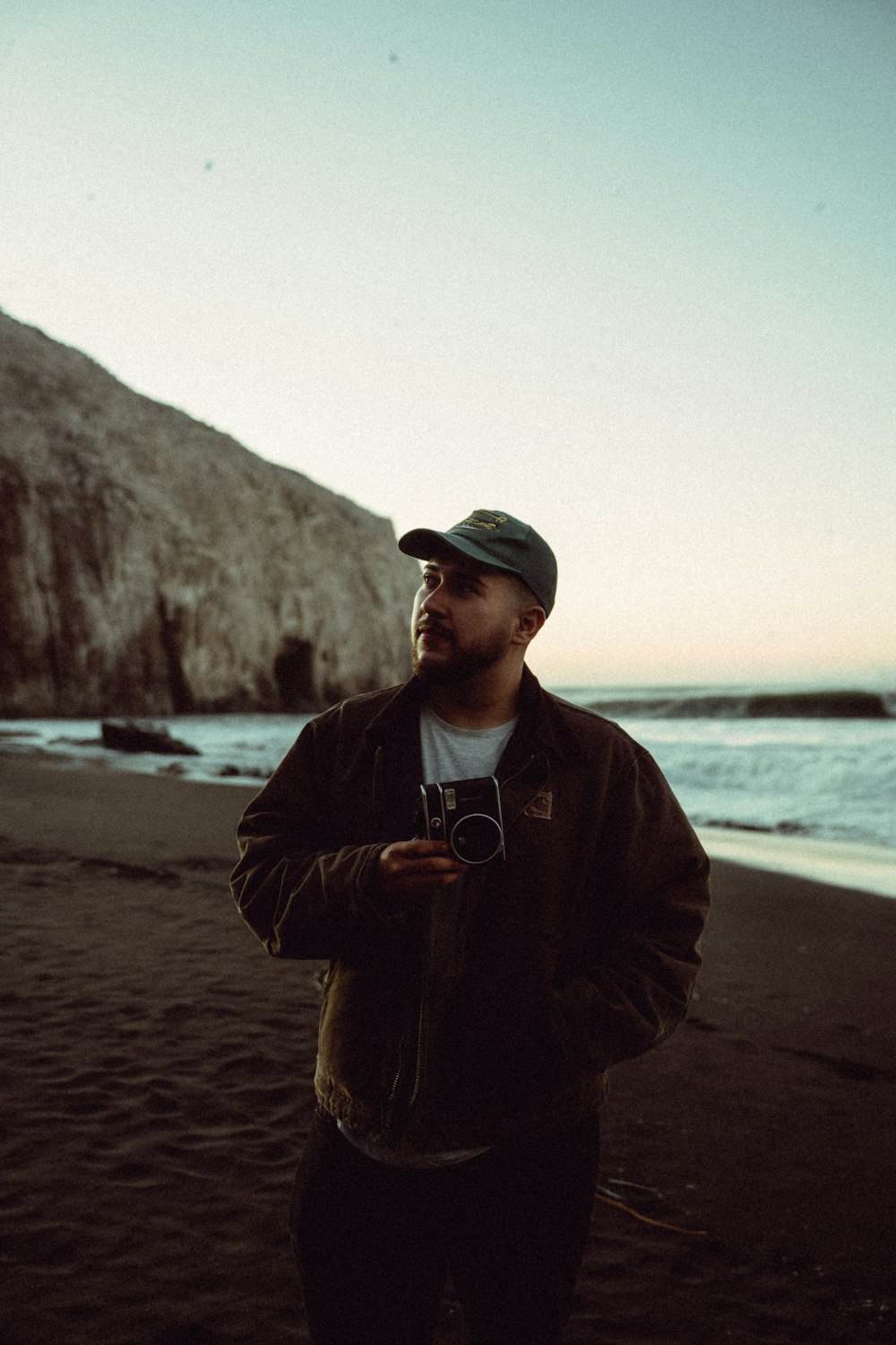 a man standing on a beach holding a camera