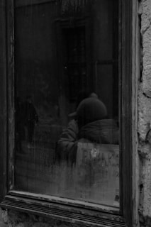 a black and white photo of a person looking out a window