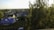 A cozy suburban neighborhood with several houses surrounded by trees. One house features a distinctive blue roof. The area is lush with greenery and bathed in warm evening light, creating a peaceful atmosphere.