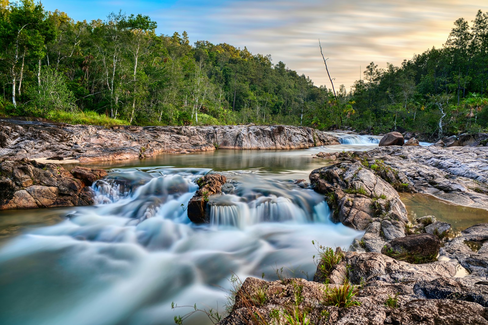 Silky long-exposure cascade over granite rocks in a forested creek at Mountain Pine Ridge