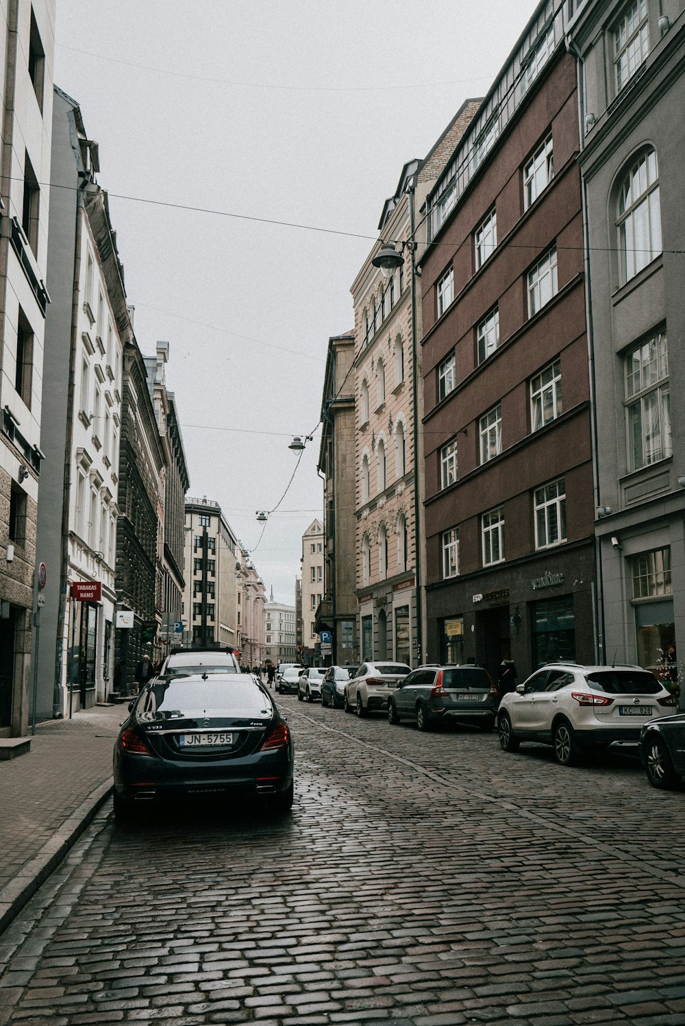 a car is parked on a cobblestone street