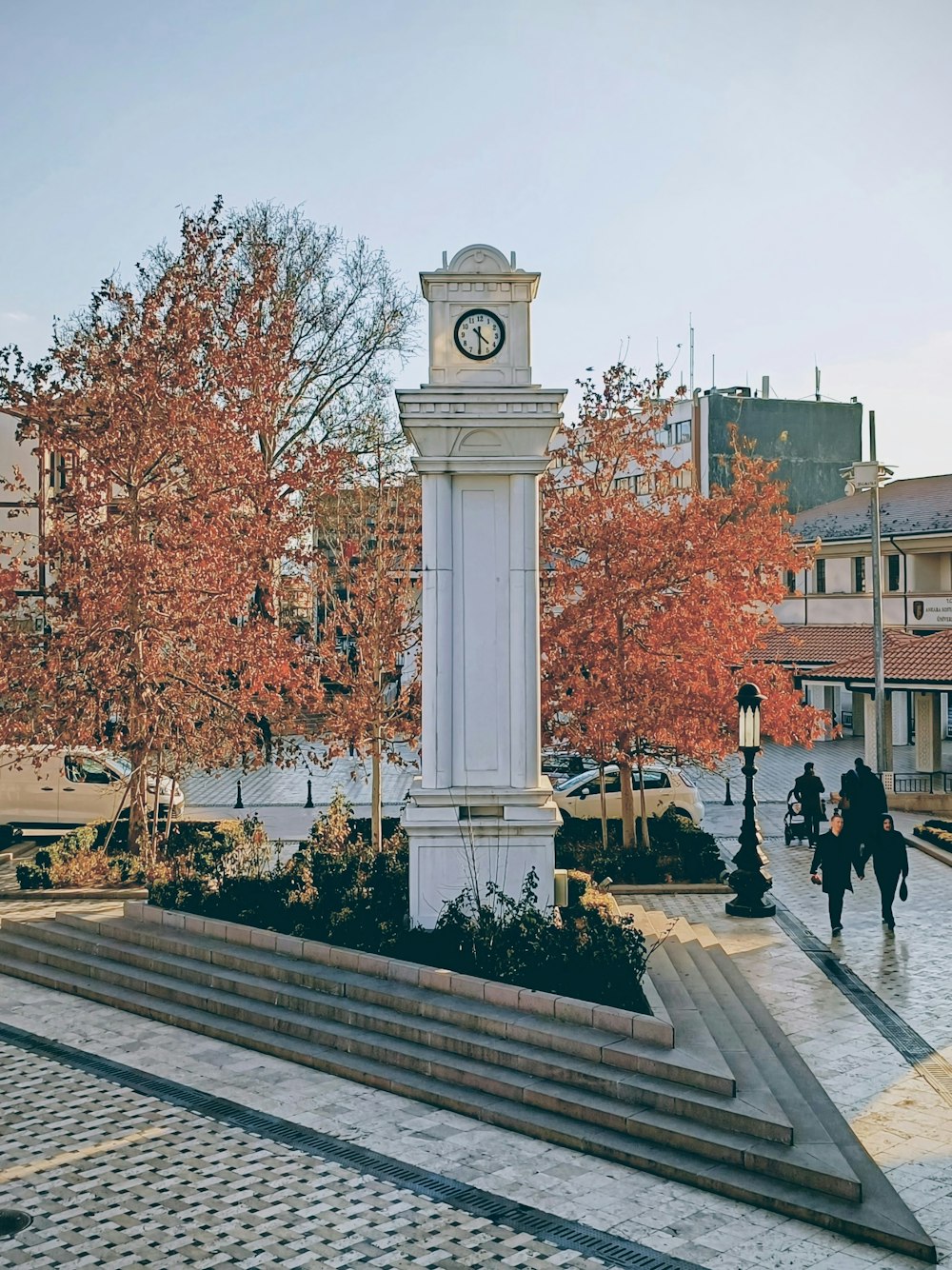 a white clock tower sitting in the middle of a park