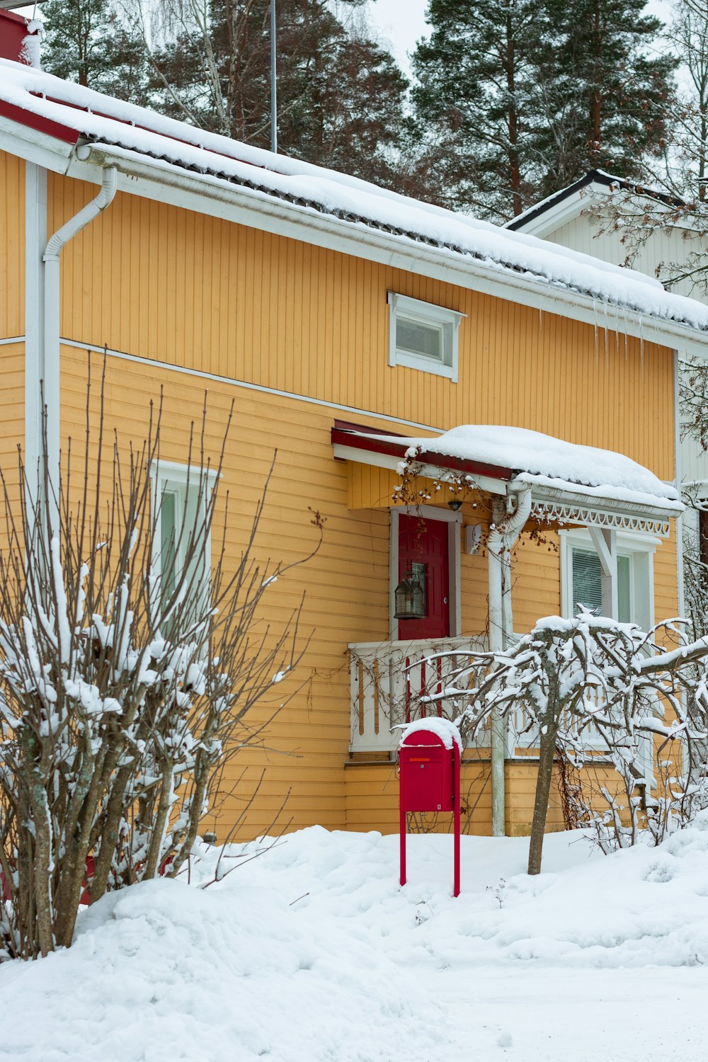 a yellow house with a red mailbox in the snow