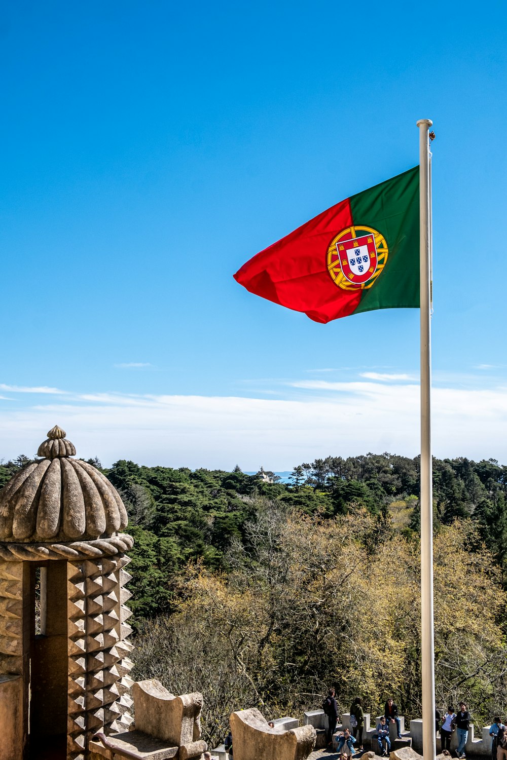 a flag flying over a stone structure in the middle of a forest