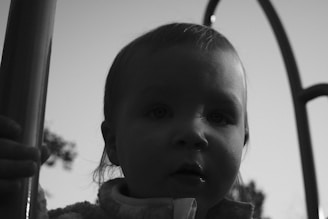 A minimalist black and white image of a child playing outdoors with soft shadows