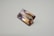 A rectangular, faceted gemstone with a transparent appearance and a gradient of colors ranging from light purple to golden brown. It is placed on a plain, light-colored surface.