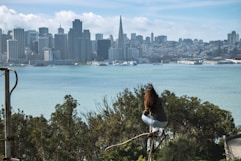 a woman sitting on a tree branch overlooking a city
