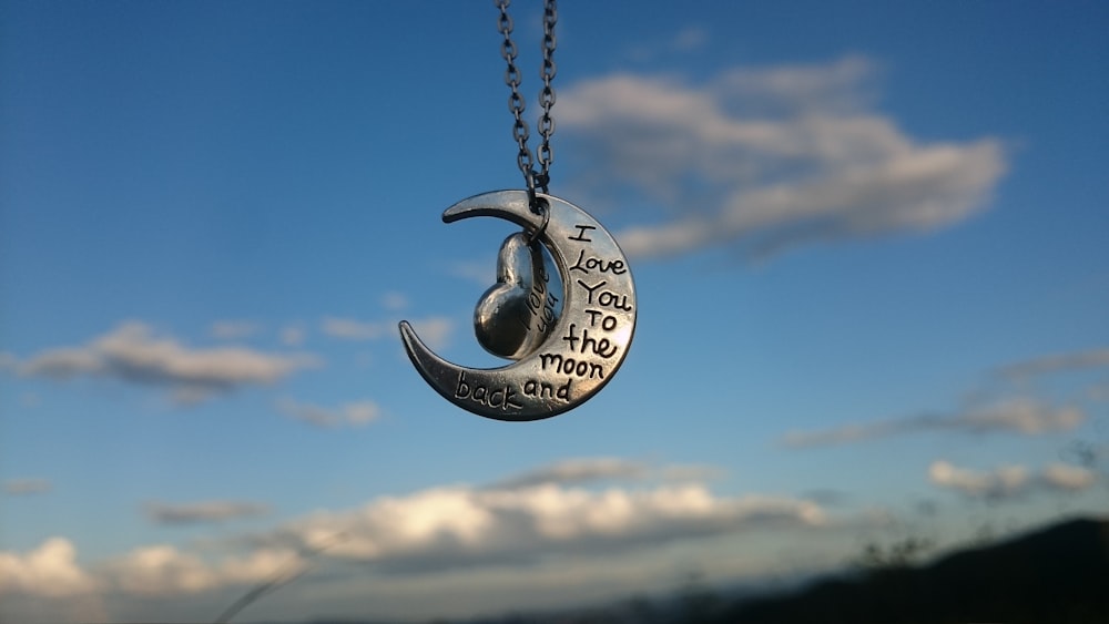 a necklace with a crescent and a quote on it