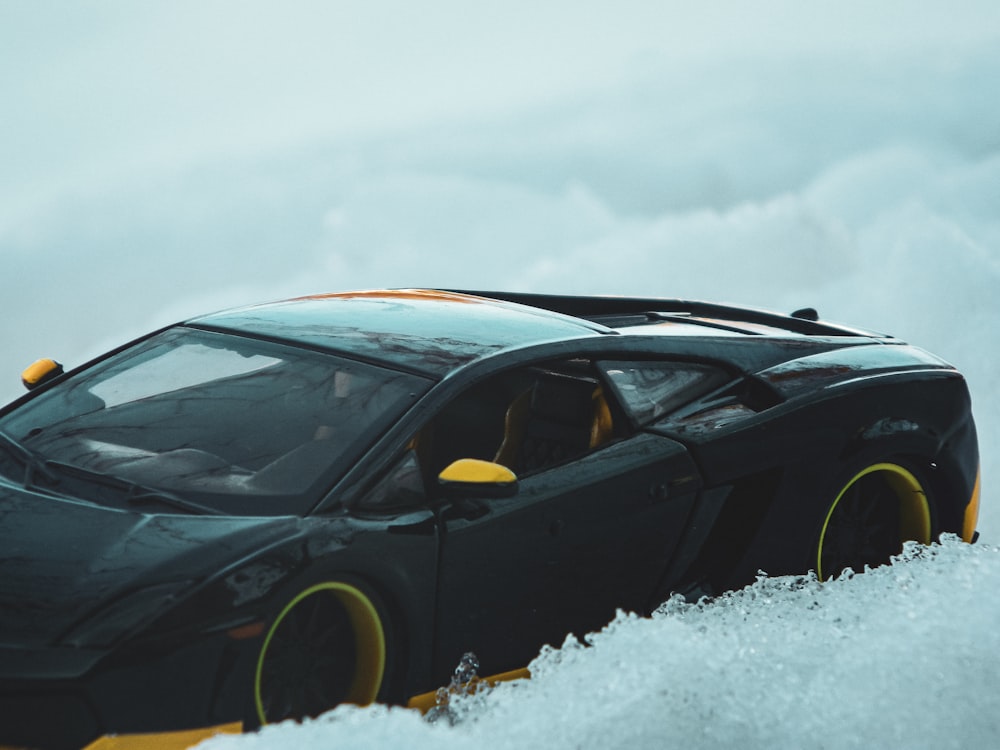 a black and yellow sports car in the snow
