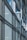 A modern architectural facade features large glass windows adorned with geometric patterns. Metal frames and beams create a grid-like structure, allowing ample light to penetrate. The design reflects urban sophistication and contemporary styling.