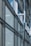 A modern architectural facade features large glass windows adorned with geometric patterns. Metal frames and beams create a grid-like structure, allowing ample light to penetrate. The design reflects urban sophistication and contemporary styling.
