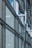 A modern architectural facade features large glass windows adorned with geometric patterns. Metal frames and beams create a grid-like structure, allowing ample light to penetrate. The design reflects urban sophistication and contemporary styling.