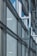 A modern architectural facade features large glass windows adorned with geometric patterns. Metal frames and beams create a grid-like structure, allowing ample light to penetrate. The design reflects urban sophistication and contemporary styling.