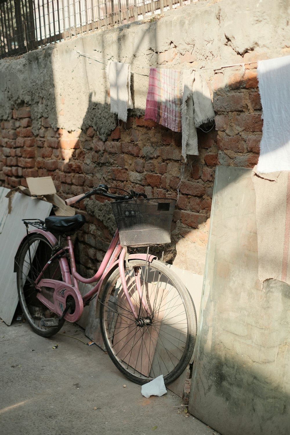 a pink bike parked next to a brick wall