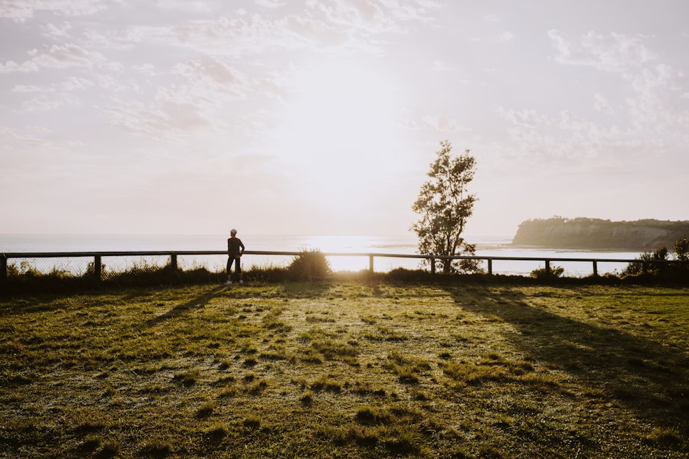 a person standing on a grass covered hill overlooking a body of water