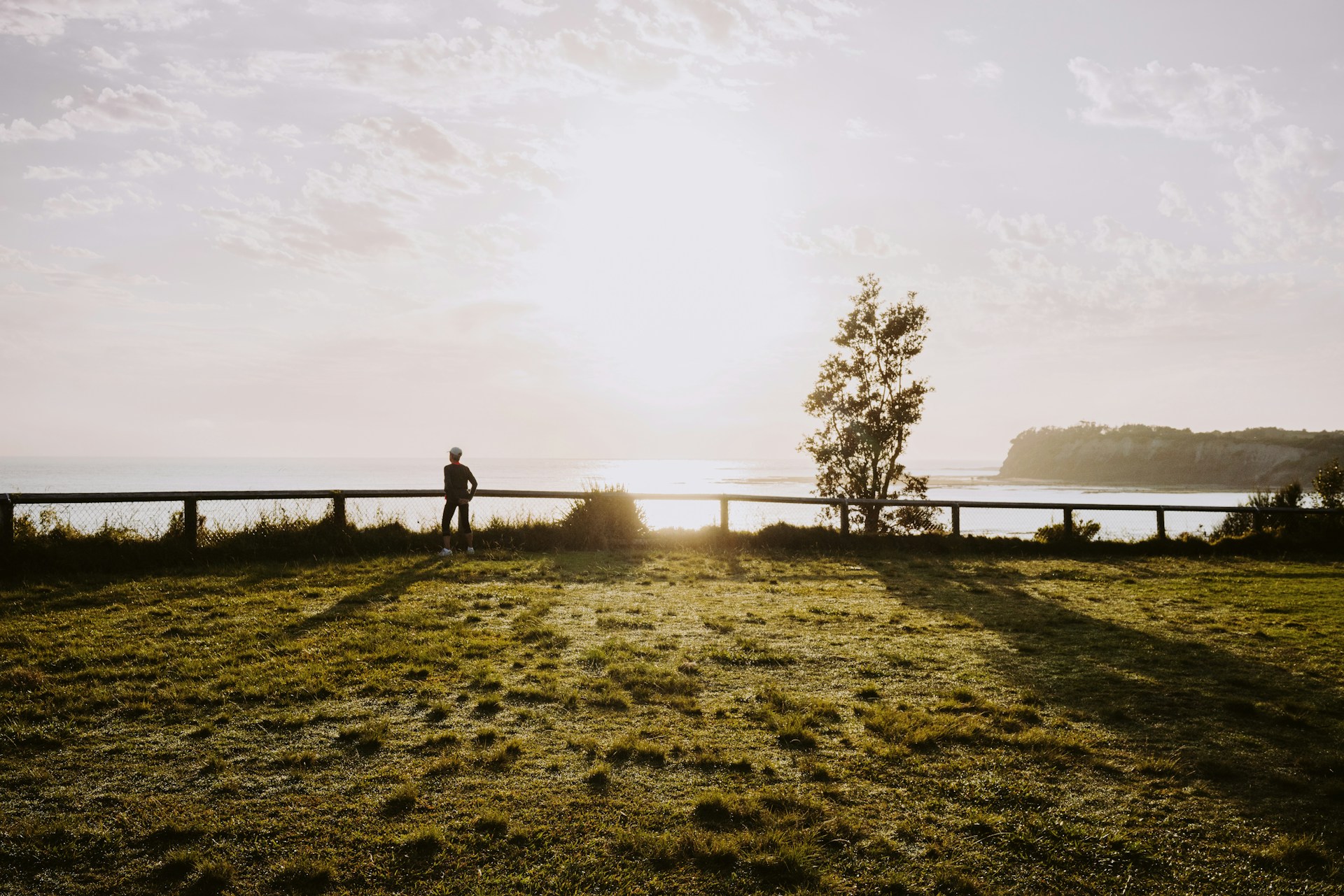 a person standing on a grass covered hill overlooking a body of water
