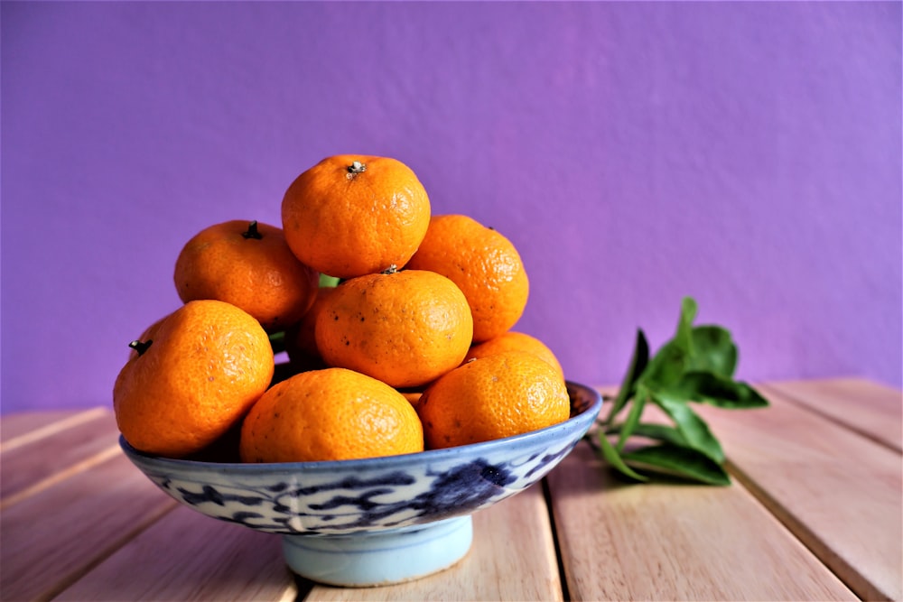 a bowl of oranges on a wooden table