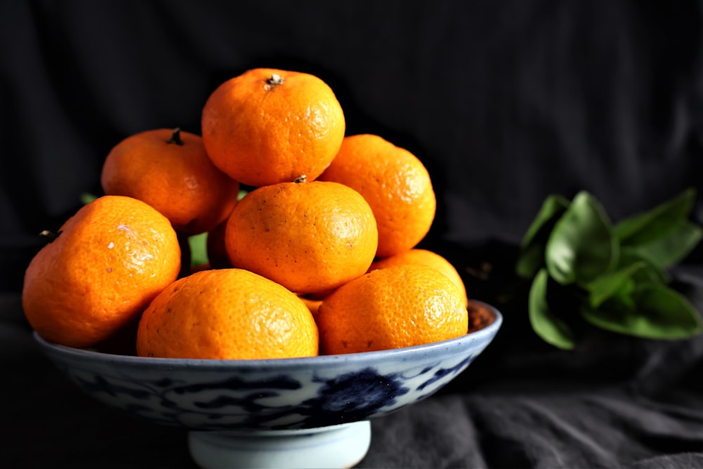a blue and white bowl filled with oranges