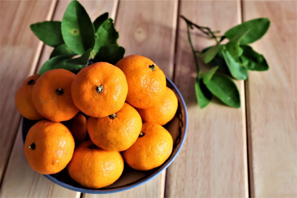 a bowl of oranges on a wooden table